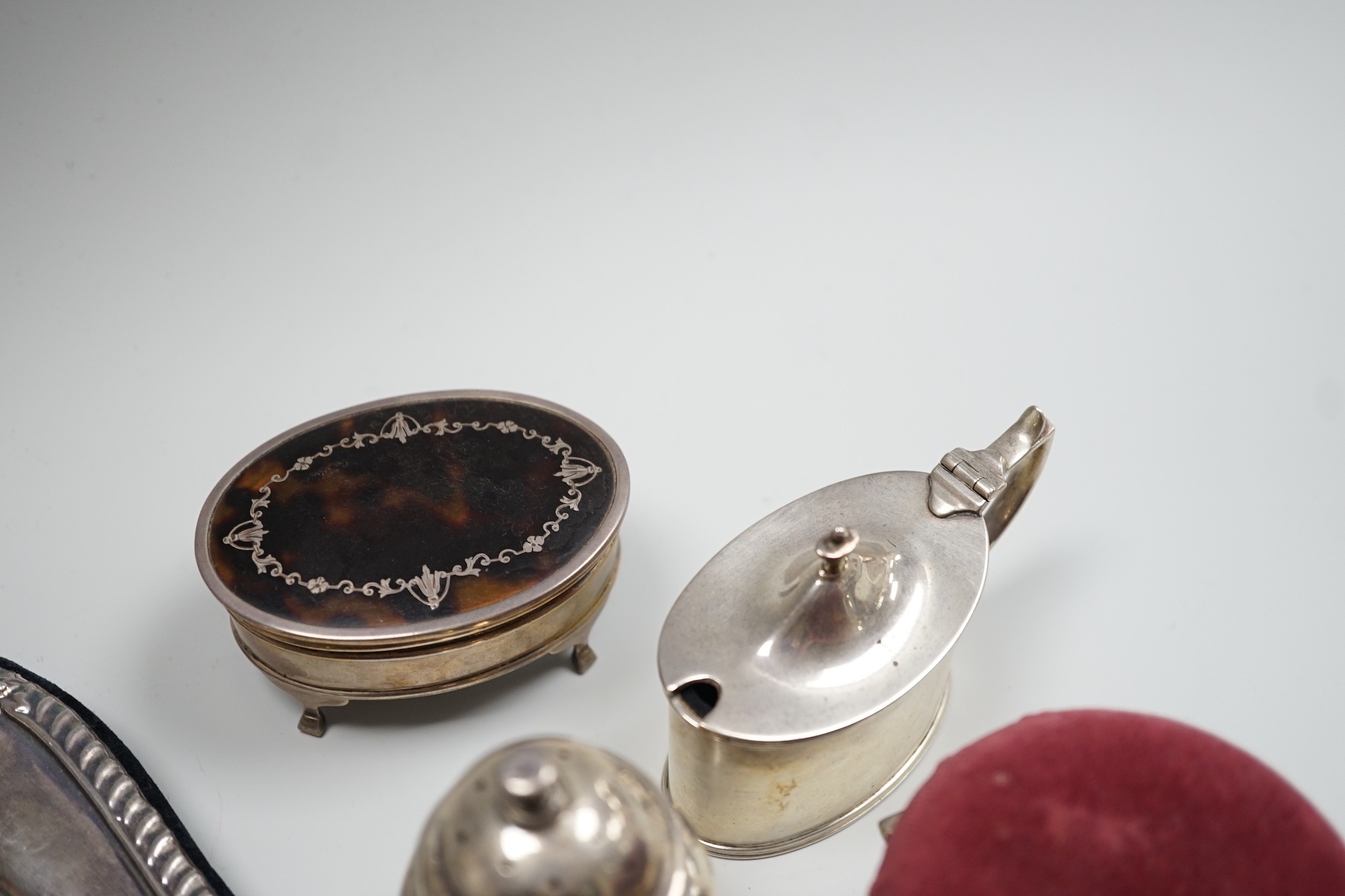 A modern silver mounted photograph frame, 30.2cm, an Edwardian silver mounted pin cushion, mustard pot, salt and a George V silver and tortoiseshell pique mounted trinket box.